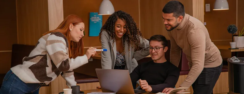 Team collaborating around a laptop at a table